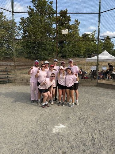 Ezrah and his slo-pitch team posing on the diamond in matching pink shirts